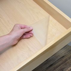 a person's hand on top of a wooden table with a piece of paper