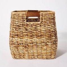 a woven basket with a wooden handle on the top and bottom, against a white background