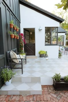 a white house with potted plants on the front porch