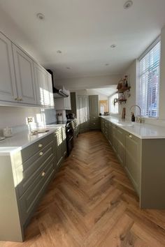 an empty kitchen with wooden floors and white cabinets