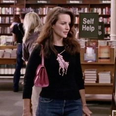 a woman walking through a library holding a pink purse