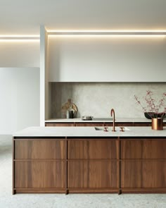 a modern kitchen with wooden cabinets and white marble counter tops, along with an island