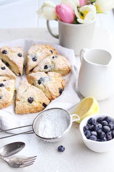 blueberry scones on a plate with lemon wedges next to it and a cup of tea