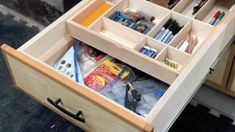 an open drawer with pens, pencils and other items in it on the counter