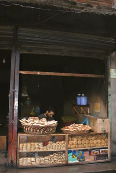 an outdoor market with breads and pastries on display in front of the store