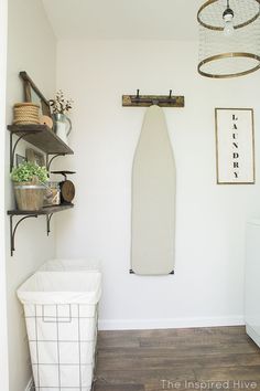 a white surfboard hanging on the wall next to a laundry basket