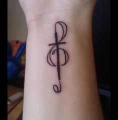 a small tattoo on the wrist of a person with a cross and musical note in it