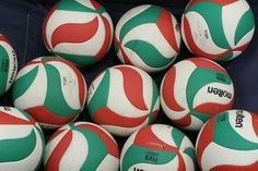 a pile of red, white and green volleyballs sitting on top of each other