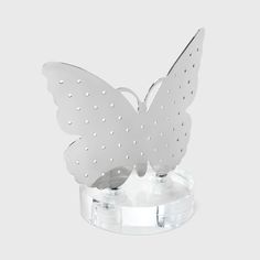 a white butterfly figurine sitting on top of a clear base with holes in it's wings