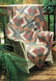 a blanket sitting on top of a wooden bench next to a potted palm tree