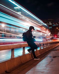 a person standing on a bridge looking at their cell phone