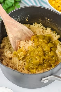 a pot filled with rice and green peppers on top of a table next to other dishes