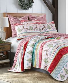 a bed covered in a colorful quilt next to a christmas wreath