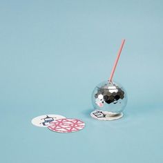 a glass ball with a straw sticking out of it sitting next to a sticker