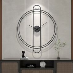 a large clock mounted to the side of a wall next to a table with a vase on it