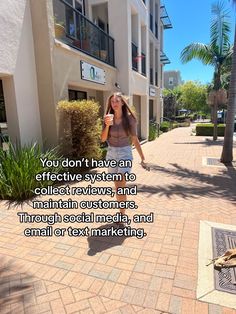 a woman walking down a sidewalk next to a tall building with a quote on it