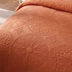 an orange quilted bedspread on a bed