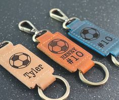 three leather key chains with soccer themed labels on them