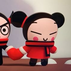 two paper dolls are holding hands in front of a white wall with black and red decorations