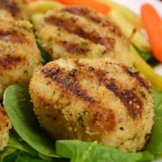 some meat patties are sitting on top of lettuce and carrots in a white plate