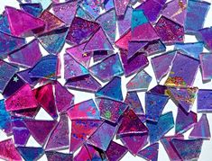 a pile of purple and blue glass mosaics sitting on top of a white table