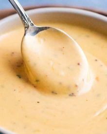 a spoon full of cream sauce in a bowl