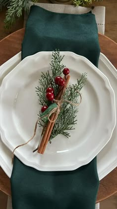 a white plate topped with cinnamon sticks and cranberry berries on top of a green napkin