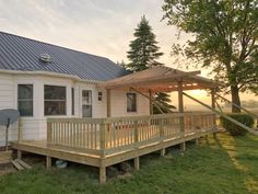 a small white house with a deck in the grass