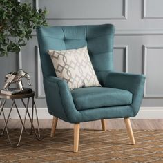 a blue chair with a pillow on top of it next to a table and potted plant