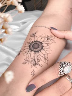 a woman's arm with a sunflower tattoo on it and a ring in the middle