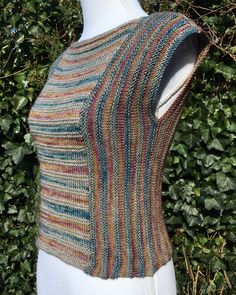 a mannequin wearing a multicolored knitted sweater on top of a white dummy