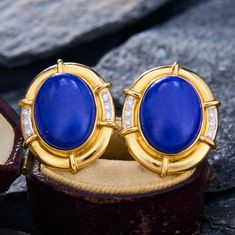 These fabulous 1980s earrings are each centered with one (1) bezel set oval cabochon cut lapis lazuli that is bordered with six (6) bead set round brilliant cut diamonds and high polished gold. The earrings measure 24.4mm by 19.2mm and are finished with omega backs and posts. 1980s Earrings, Lapis Lazuli Earrings, Bead Set, Oval Cabochon, Round Brilliant Cut Diamond, Brilliant Cut Diamond, Bezel Setting, Round Brilliant, Lapis Lazuli