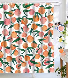 a shower curtain with oranges and green leaves on it in a white room next to a potted plant