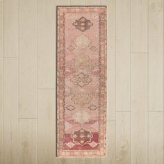 a pink rug hanging on the wall in a room with wood flooring and white walls