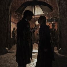 two people standing under an umbrella in the rain