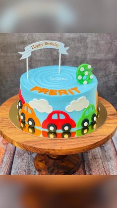 a birthday cake with cars on it sitting on top of a wooden table next to a sign