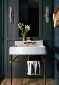 a white sink sitting under a bathroom mirror next to a wooden floor and blue walls