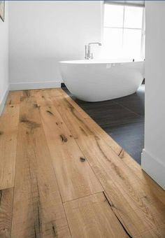 a white bath tub sitting on top of a wooden floor