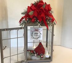 a candle holder with a red bow and christmas decorations on it, in front of a white wall