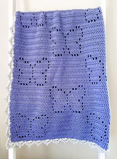 a blue crocheted blanket hanging on a white chair in front of a wall