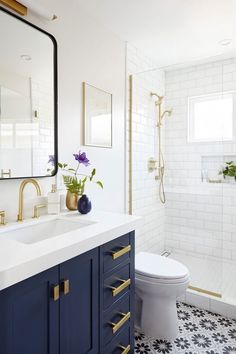 a white toilet sitting next to a bathroom sink under a mirror and a blue cabinet