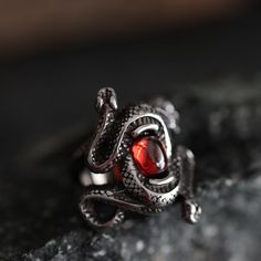 Enter the mystique with our Double Snake Ruby-Style Red Stone Gothic Ring--a mesmerizing fusion of gothic allure and intricate design. Crafted from durable stainless steel, this ring features two snakes coiled around a captivating ruby-style stone, creating a bewitching symbol of transformation and mystery.  Perfect for the woman who adores the enigmatic, this ring is not just an accessory but an extraordinary present that speaks volumes about her unique style and untamed spirit. -- Shipping inf Black Fantasy Rings As Gift, Black Fantasy Style Rings As Gift, Fantasy Style Black Ring For Gift, Gothic Stainless Steel Metal Ring Jewelry, Adjustable Gothic Snake Ring As Gift, Adjustable Gothic Snake Ring For Gift, Snake-shaped Metal Rings As A Gift, Adjustable Gothic Stainless Steel Rings, Halloween Stainless Steel Ring Jewelry