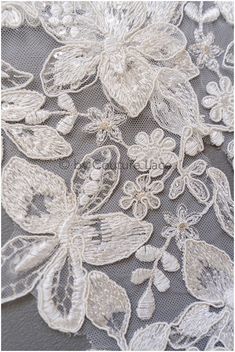 an embroidered lace with flowers and butterflies on it's side, is shown in white