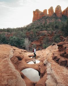 a man standing on top of a rock formation next to a small pool of water