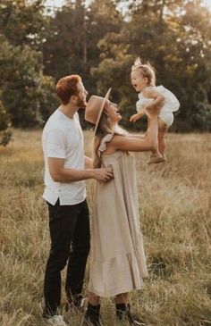 a man and woman holding a baby in a field