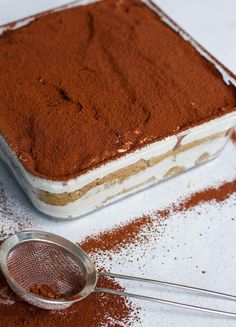 a cake in a pan and a strainer on the ground with powdered sugar