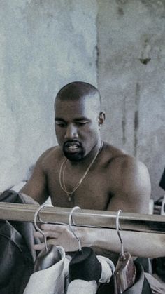 a shirtless man sitting on top of a bed next to some pairs of shoes