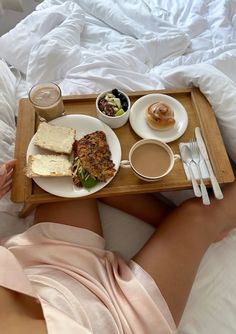 a person laying in bed with food and drinks on a tray next to their stomach