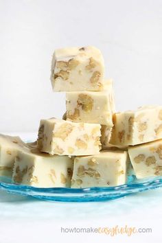 pieces of fudge are stacked on top of each other in a blue plate with the words maple walnut fudge above it