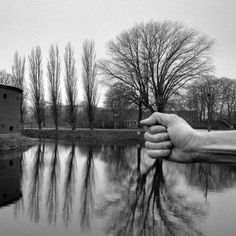 a black and white photo of two hands holding each other's hand over a body of water